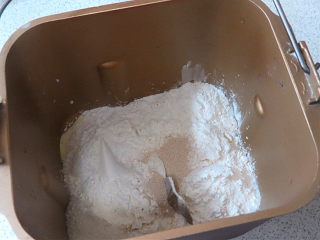 萌趣。【双色小熊挤挤面包】,先来和面，把白面团中除黄油外的所有食材按照底层液体、中层粉类、上层干酵母的顺序全部放入面包机桶里