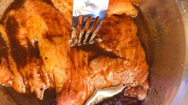 炭烧猪颈肉,用叉子在肉厚的地方多插几个洞，让腌料渗入。