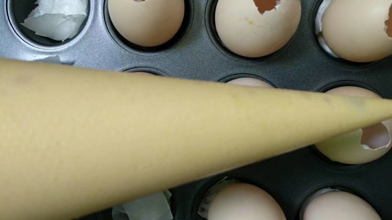 萌萌小鸡蛋糕,模具里提前垫上一点油纸固定鸡蛋，蛋糕糊装入裱花袋。