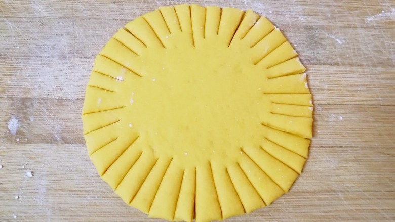 向日葵馒头,取一个黄色的小剂子擀成圆饼状，在圆饼的周围用刀对称着分成12份，再把每一小份分成三份。