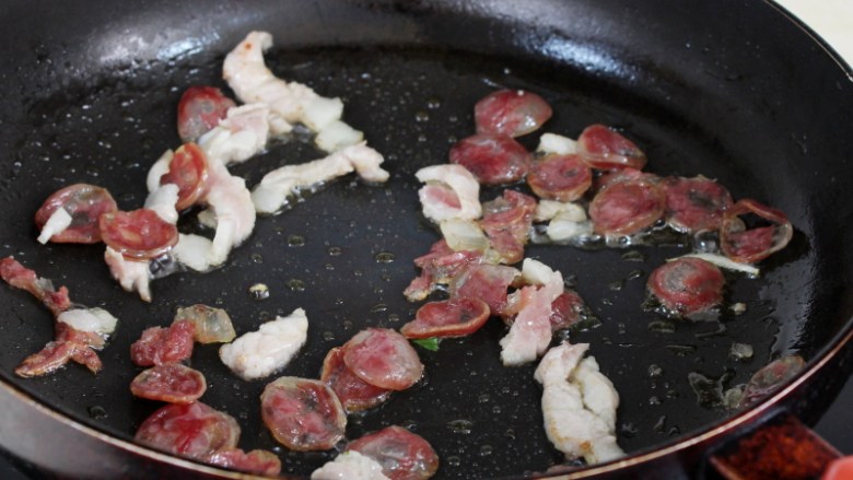 干煸花菜,锅里再倒些油，微热时下香肠和肉，用小火煸到香肠透明。
