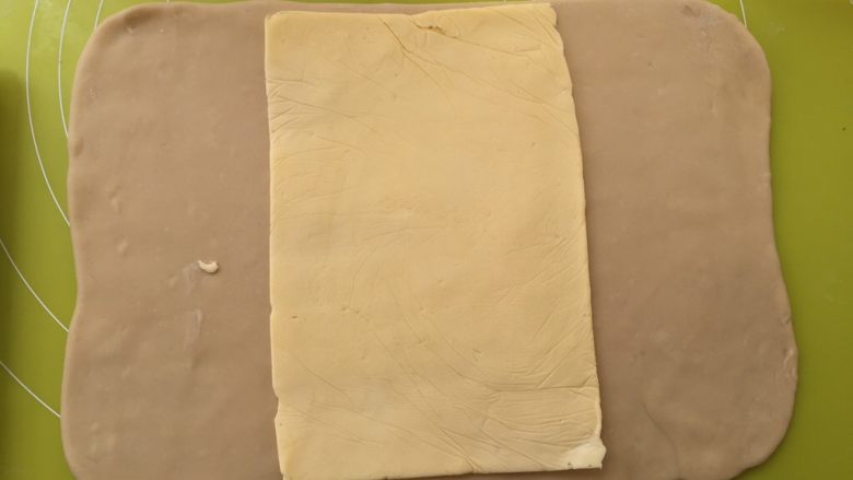 起酥小面包,冰箱取出冷冻的面片跟黄油，用剪刀将包裹黄油的保鲜袋裁开，将黄油片铺在面片中间