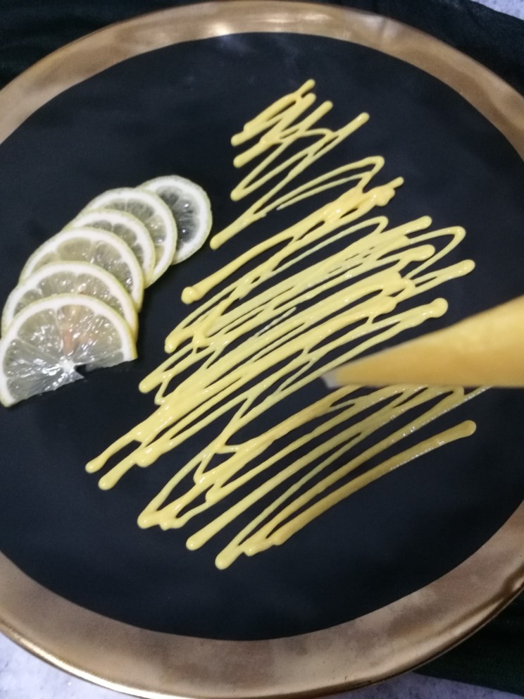 柠香煎鳕鱼,把剩下的半个柠檬摆盘装饰，用裱花袋挤上柠檬芒果汁铺底。