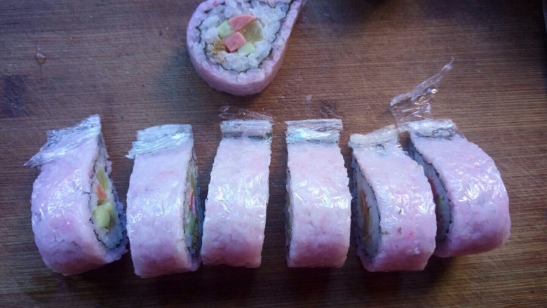 樱花寿司,切寿司的时候，保鲜膜不要揭下来，这样切的寿司整齐不容易散掉，要用比较锋利的刀切。