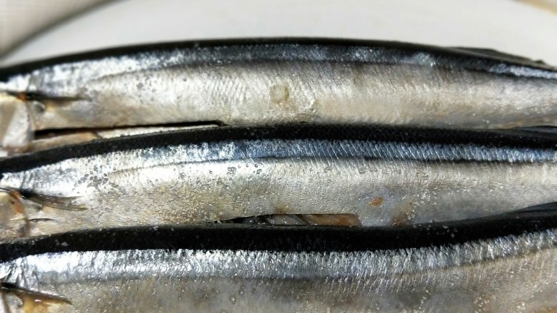 香煎秋刀鱼,洗净的秋刀鱼表面抹一点点盐腌几分钟