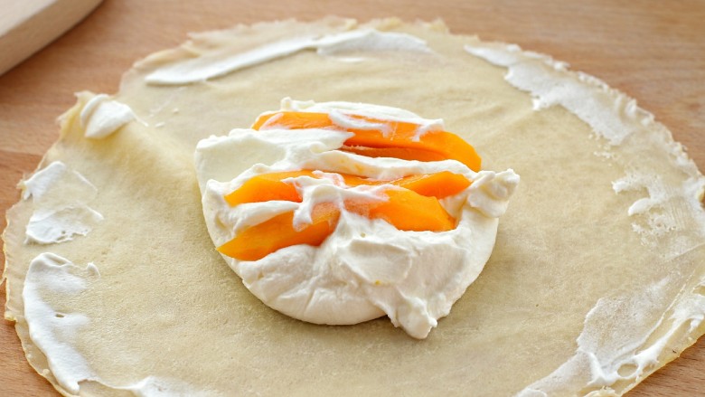 芒果班戟,取一张饼皮，把光滑的一面放在下面，中间放适量淡奶油，再放上芒果，边缘涂一些淡奶油