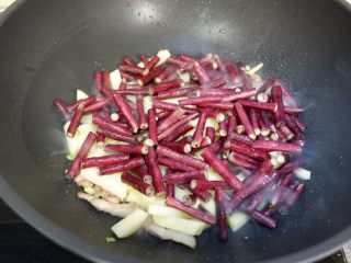 紫豆角烧土豆条,加入豆角、土豆条、料酒翻炒1分钟
