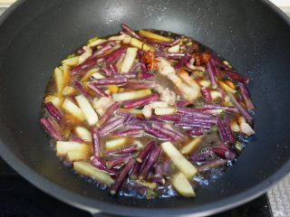 紫豆角烧土豆条,加入清水、生抽、老抽、白糖，大火煮开后