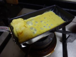 日式厚蛋烧,待蛋液半凝固卷起来，倒入第二层鸡蛋液。