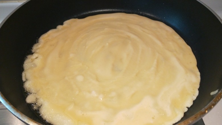 鸡蛋卷饼,在舀一大勺面糊摊开。