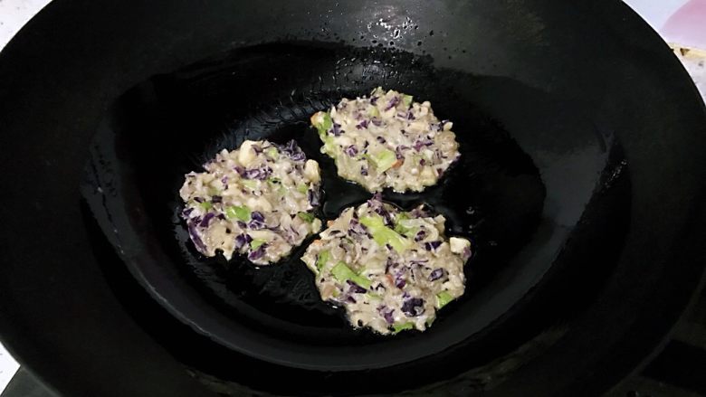 紫甘蓝鸡蛋肉饼,调小火，用小勺挖一勺，入锅中摊圆摸平。