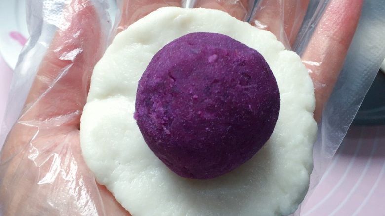 紫薯糯米饼,取一份糯米皮用手掌心按扁，放上一个紫薯泥