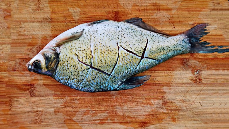 红烧武昌鱼,处理好的鱼，用干布将水分吸干，在表面划上几刀，方便其入味。