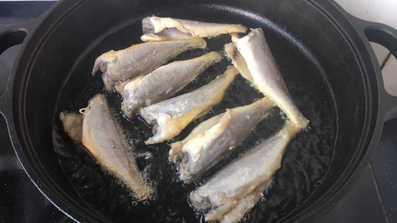 铁锅版红烧小黄花鱼,锅里放适量的油，油5、6成热时拎着鱼尾轻轻的贴着油面放到锅里。