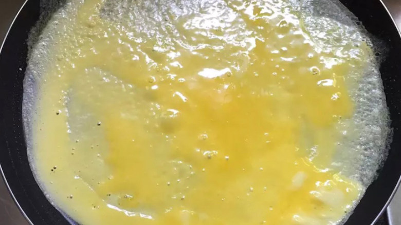 秋葵厚蛋烧,取蛋液倒入平底锅，轻轻晃动，使蛋液铺满平底锅。