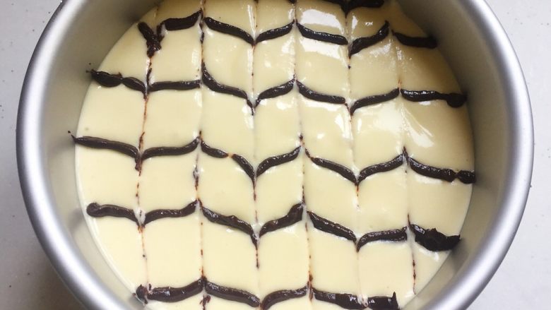 大理石纹芝士蛋糕,把黑巧和另外5g淡奶油融化后倒入裱花袋，先在蛋糕糊上拉出横条纹，再用牙签按“一来一去”的方法划出花纹