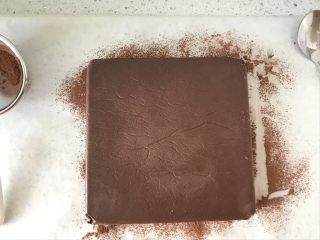 生巧,台面上铺上油纸，晒一些可可粉，把冷冻好的巧克力取出，撕掉油纸，倒扣在撒好可可粉的油纸上。