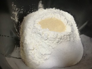 酸奶小餐包,接下来加入奶粉、高筋面粉，糖和盐对角放，面粉中间挖个小坑放入干酵母，用面粉盖上。