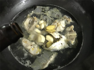 红烧鲶鱼,煮开后撇去浮沫，把老姜和大蒜放入，再倒入适量料酒。