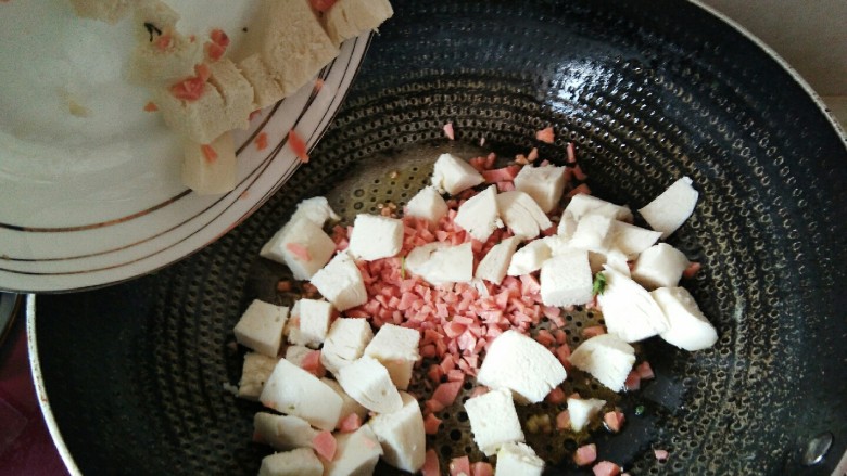 “炒馒头”有滋有味更健康,将馒头块和火腿丁放在热锅里。
