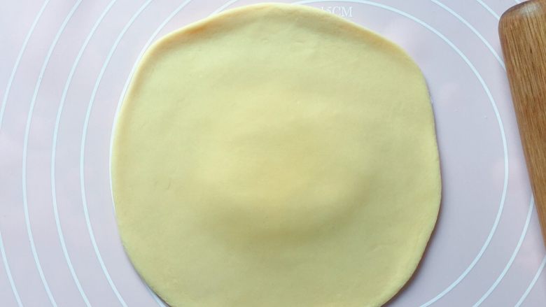 梅干菜麦饼,取一份面团，用擀面杖擀成中间稍厚边缘薄一点的饼皮。