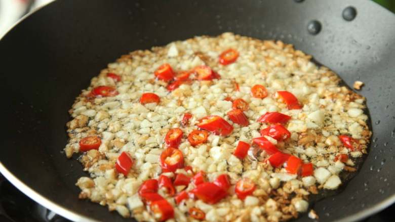 有家鲜厨房：小满养生菜 蒜蓉丝瓜,热锅倒入适量油，炒制大蒜和小米椒，炒制过程中放入食盐