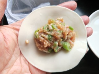 豆角猪肉馅饺子,手上蘸清水，沿饺子皮抹一圈，放适量的饺子馅。