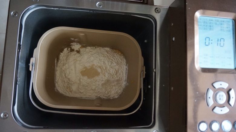 芒果面包卷,在面粉顶端加入酵母，将面包桶放入到面包机里，选择和面10分钟。