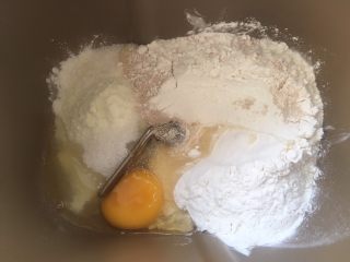 红豆包,面包桶内加入高筋面粉，低筋面粉，奶粉，炼乳，鸡蛋，细砂糖根酵母，加水启动揉面程序活成面团