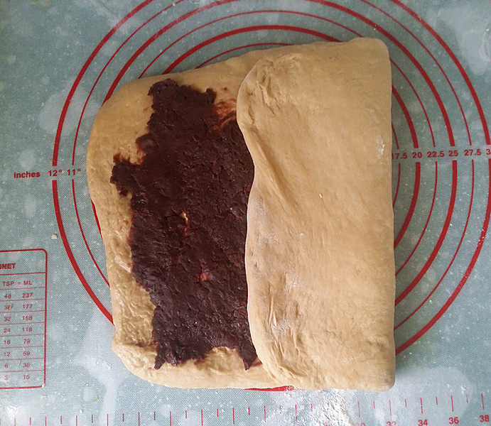咖啡酸奶豆沙面包 #独创配方、全新做法# ,先将右边空白部分向中间折叠，再将左边面团折上，成一个竖的长方形