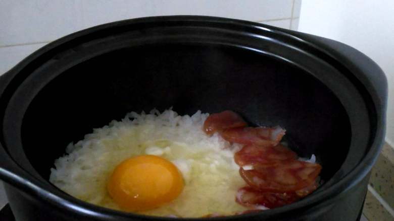 腊味煲仔饭,腊肠基本成熟，米饭开始出现小洞时，打入一个鸡蛋。
