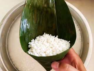 北方传统粽子,在粽叶里面加入浸泡好的糯米，糯米加到粽叶的2/3处即可，再加入清水，让米粒下沉，减少空隙