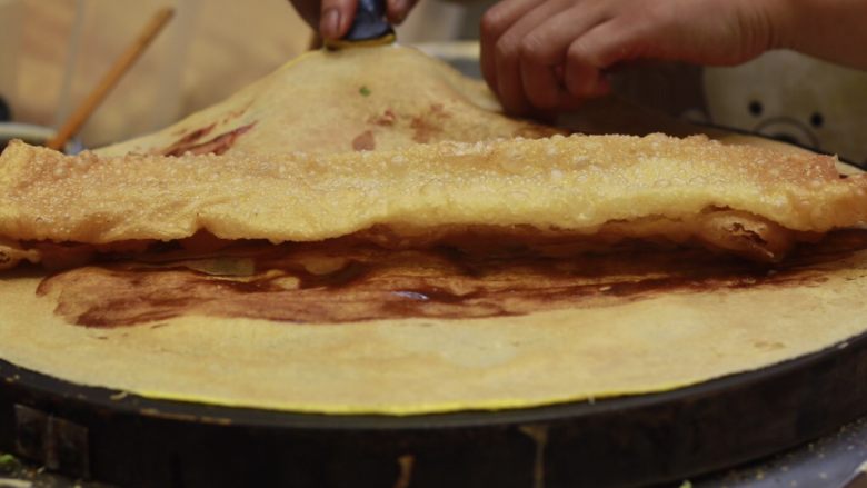 美味早餐 妈妈味道的绿豆煎饼果子,放上准备好的果蓖，用煎饼裹上果蓖。