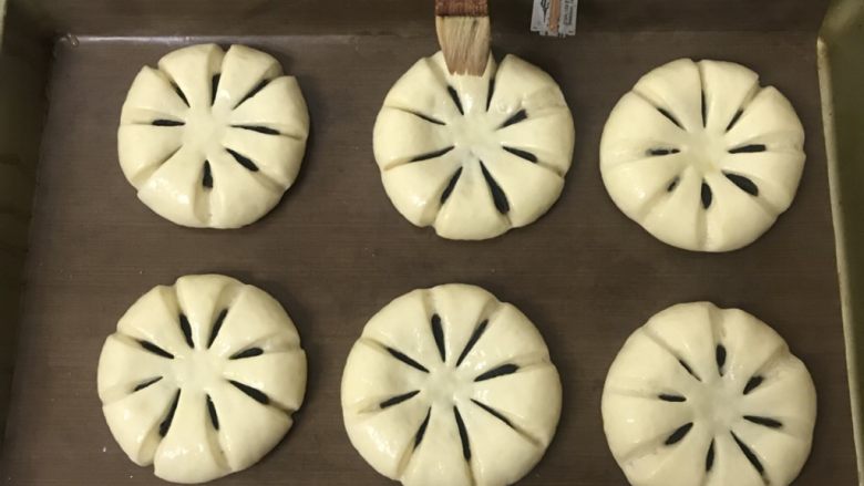 豆沙花朵面包,送进发酵箱湿度保持在80％左右，温度在35度发酵一倍大，表面刷上蛋液，看好割包刀自制的。