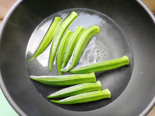 秋葵炒蛋,锅里烧适量热水，放入秋葵，烫两分钟