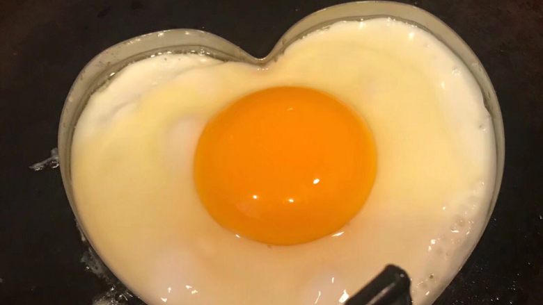 手抓饼开心早餐,锅中倒入适量底油加热摆入心形模具打入鸡蛋