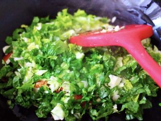 培根鸭蛋杂蔬炒饭,再加入用刀切碎的莴苣叶继续翻炒片刻，直至看见包菜和莴苣叶断生变色时；