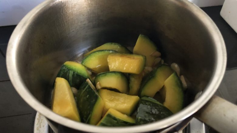 小奶锅煮日式南瓜,颠一下锅，再干煎一分钟。开盖，南瓜块边缘略焦即可进行后续步骤。
