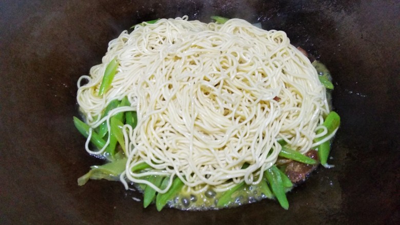 豆角焖面,面条吸收汤汁，用筷子将面条翻动。