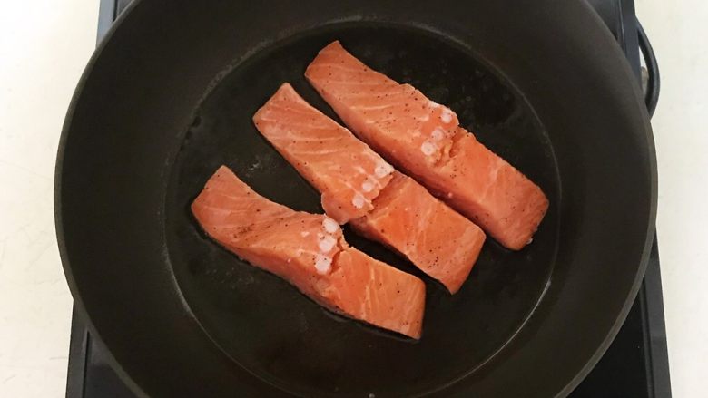 减脂健身菜  柠香黑椒三文鱼果蔬沙拉,橄榄油烧热后加入三文鱼，煎至一面变色就翻面，