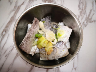 香煎带鱼,带鱼撒上葱花和姜片，再倒入白酒拌匀，腌制30分钟，