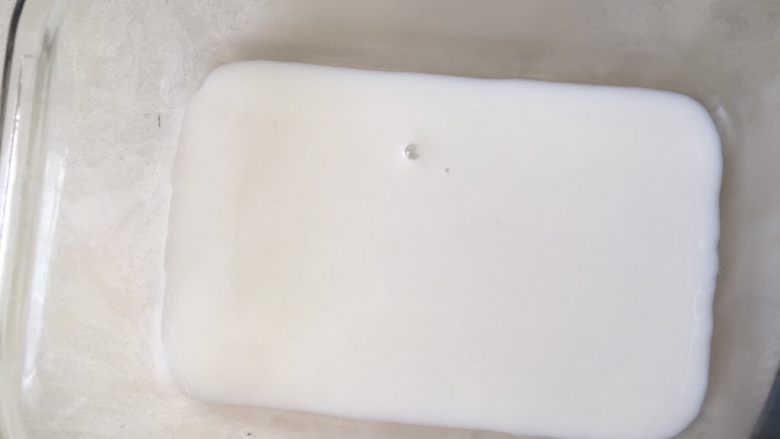 芒果千层糕,我用的方形玻璃保温盒，擦干净，倒入薄薄的一层牛奶，入冰箱冷藏至凝固