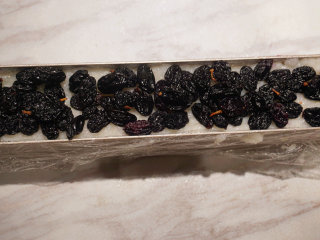 蔓越莓糯米糕,按照一层糯米，一层果干的方式均匀压平，铺上黑加仑

