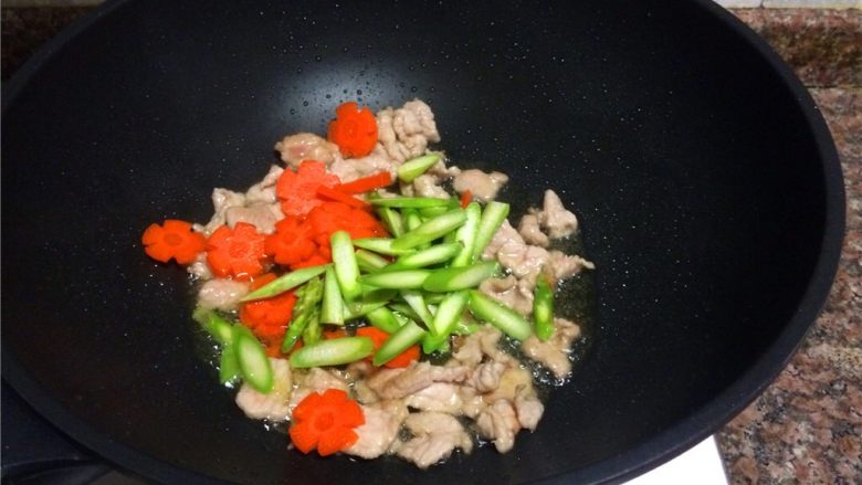 双耳菜花炒肉片,放入胡萝卜片和芦笋翻炒20秒。