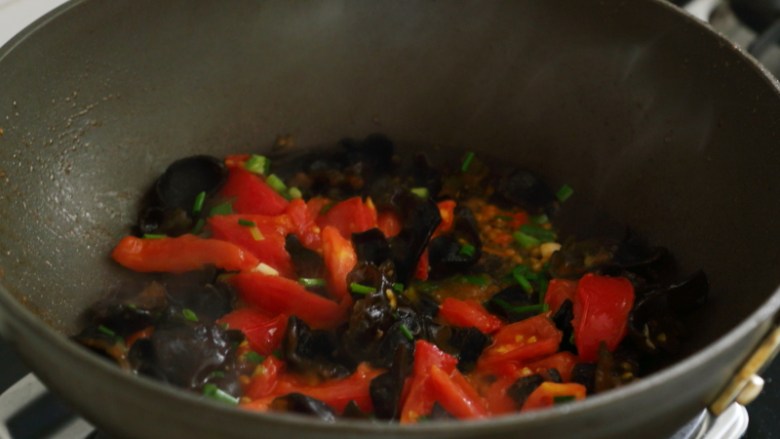 杂蔬鸭汤手擀面,锅里再倒油烧热，先下小葱，再下西红柿，西红柿炒软了后下木耳翻炒。
