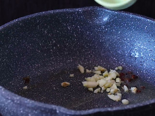 干煸四季豆,炒锅中放入适量食用油。爆香花椒粒和姜蒜末