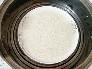 腊肉香菇糯米烧麦,泡好的糯米放在深一点的盘子里，加入和糯米一样高的水上锅蒸半个小时晾凉备用。
