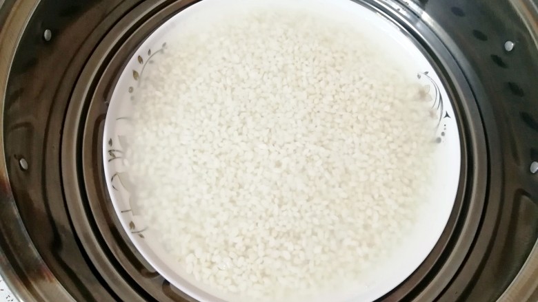 腊肉香菇糯米烧麦,泡好的糯米放在深一点的盘子里，加入和糯米一样高的水上锅蒸半个小时晾凉备用。