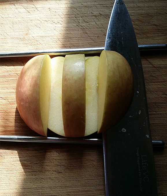 天鹅戏水,如图将刀贴着筷子，横切至竖切面交汇处，这样就切下左、右两小块苹果，剩下的部分：则是用来做天鹅身体的