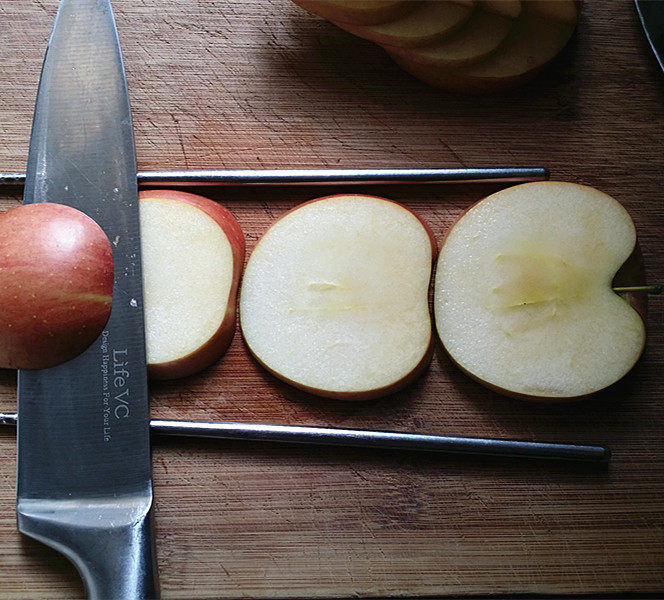 天鹅戏水,将另一半苹果，切面朝下放至2根筷子中间，贴着筷子将苹果横切成4片